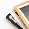 A wooden and black frame displaying a piece of art, showing the magnetic front-open design.