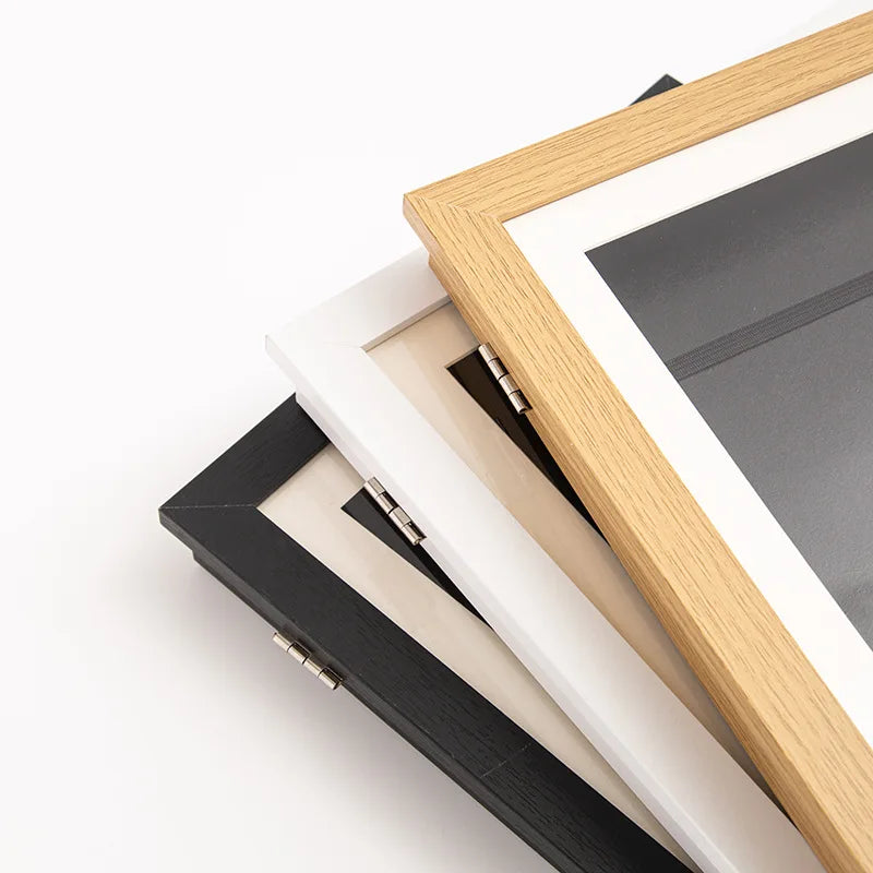 A wooden and black frame displaying a piece of art, showing the magnetic front-open design.