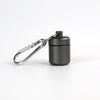 A small, black, cylindrical pill organizer is attached to a silver keychain ring.