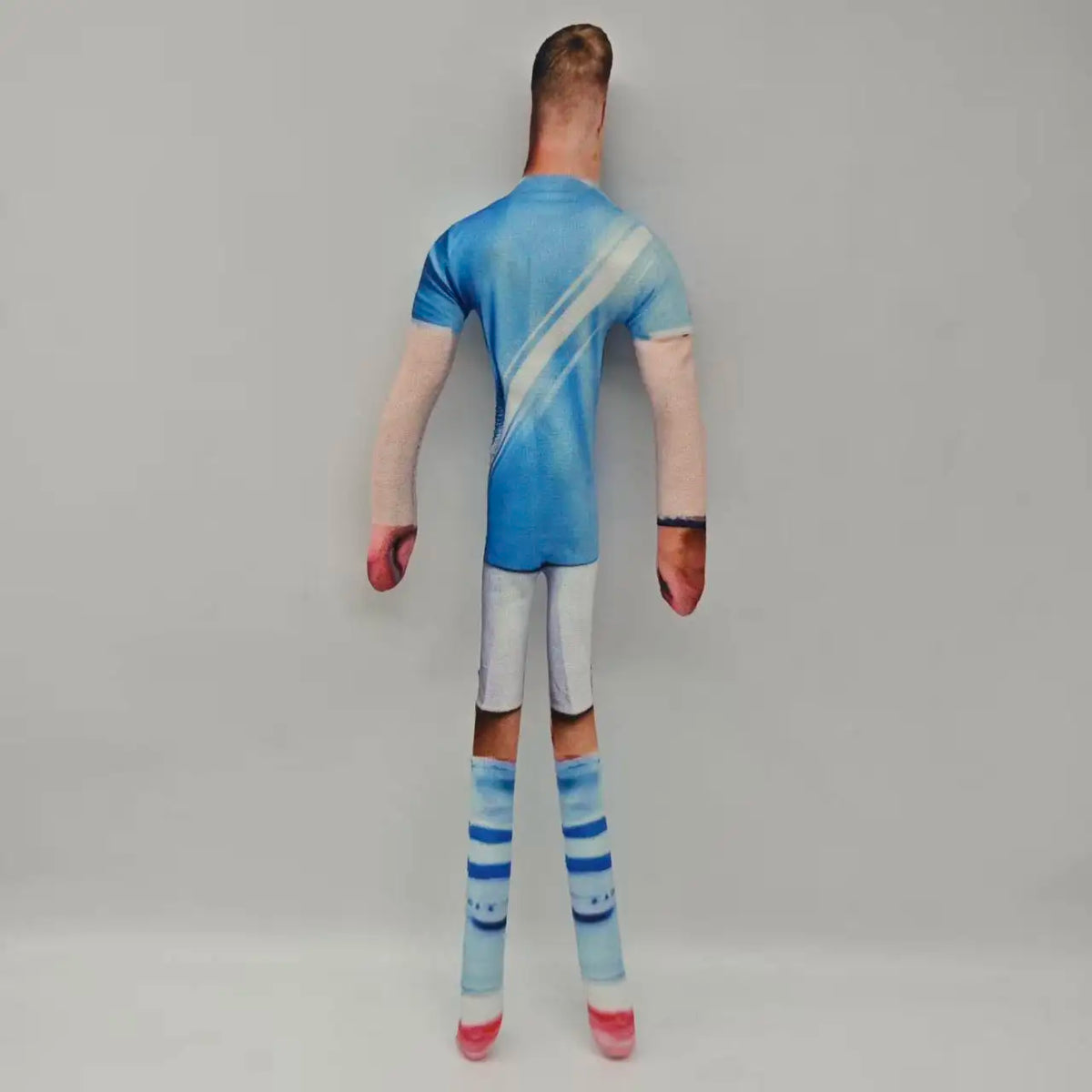 Una persona con camiseta azul y pantalones blancos con calcetines a rayas de espaldas.