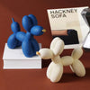 A pair of blue and white balloon dog resin sculptures displayed next to a magazine featuring the Hackney Sofa.