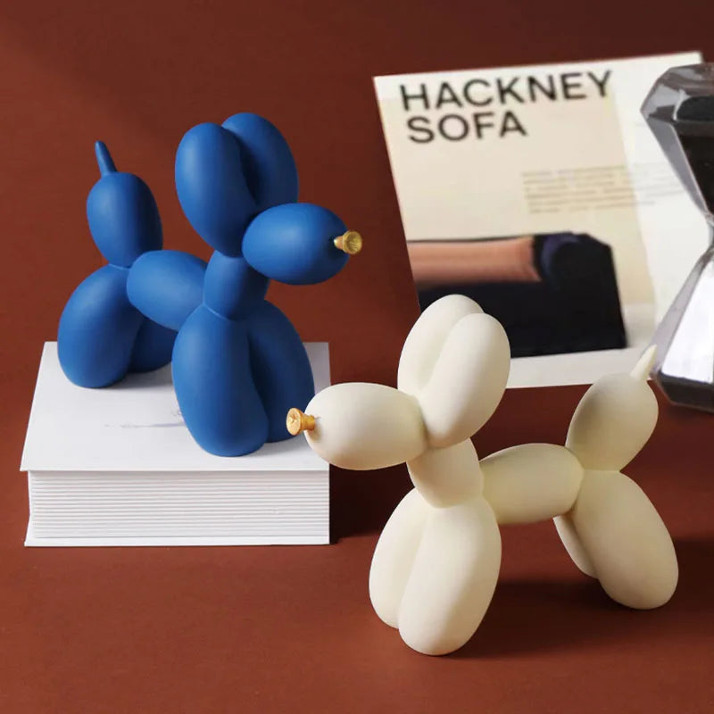 A pair of blue and white balloon dog resin sculptures displayed next to a magazine featuring the Hackney Sofa.