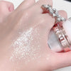 A hand is applying fairy body glitter highlight powder to the skin, showing a sparkling finish.