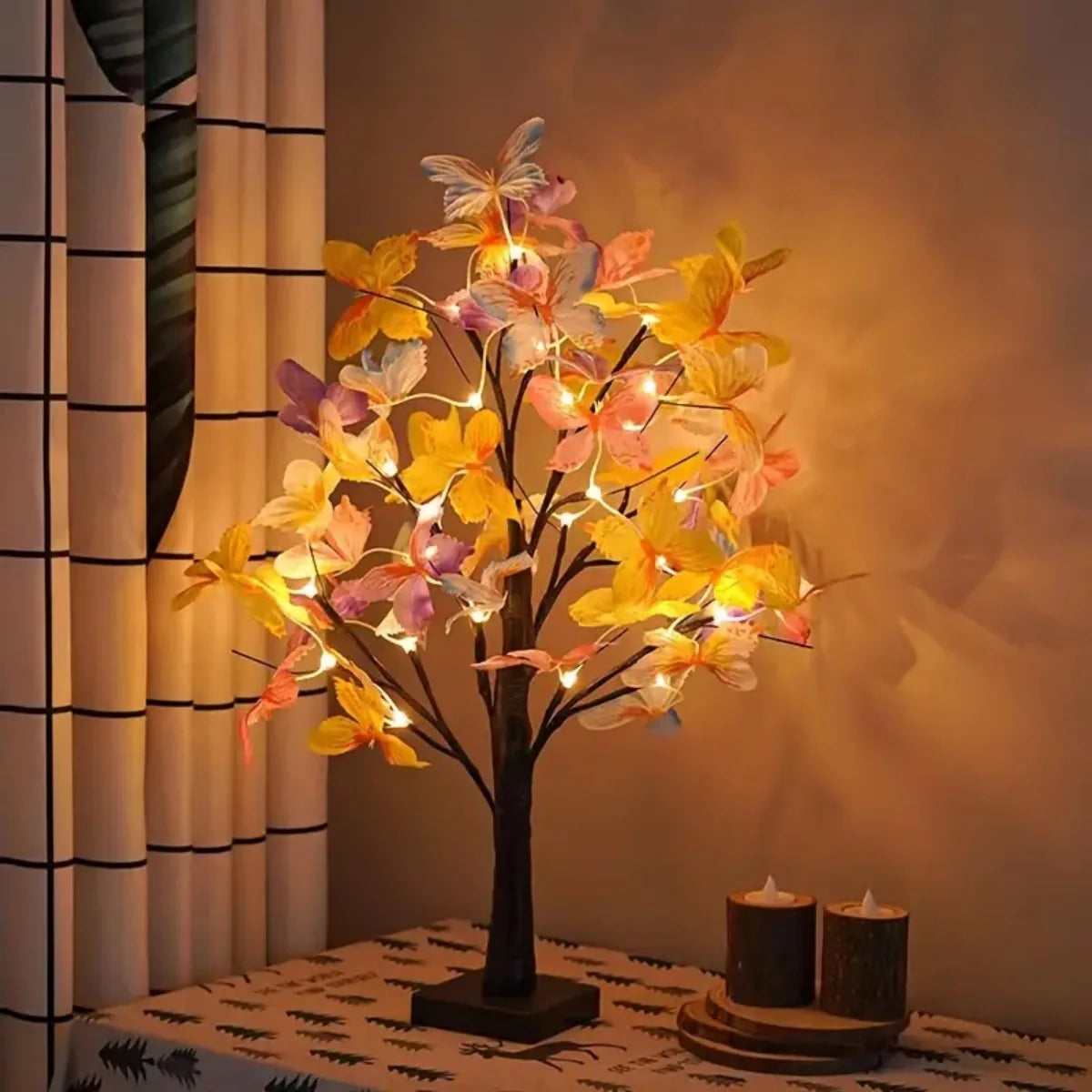 A decorative tree light shaped like a birch tree with illuminated butterfly-like leaves casting a warm glow.