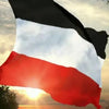 A German Empire flag with horizontal black, white, and red stripes waving against a bright sky.