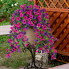 A vibrant silk morning glory vine wreath featuring pink and purple flowers draped over a terracotta urn against a wooden trel