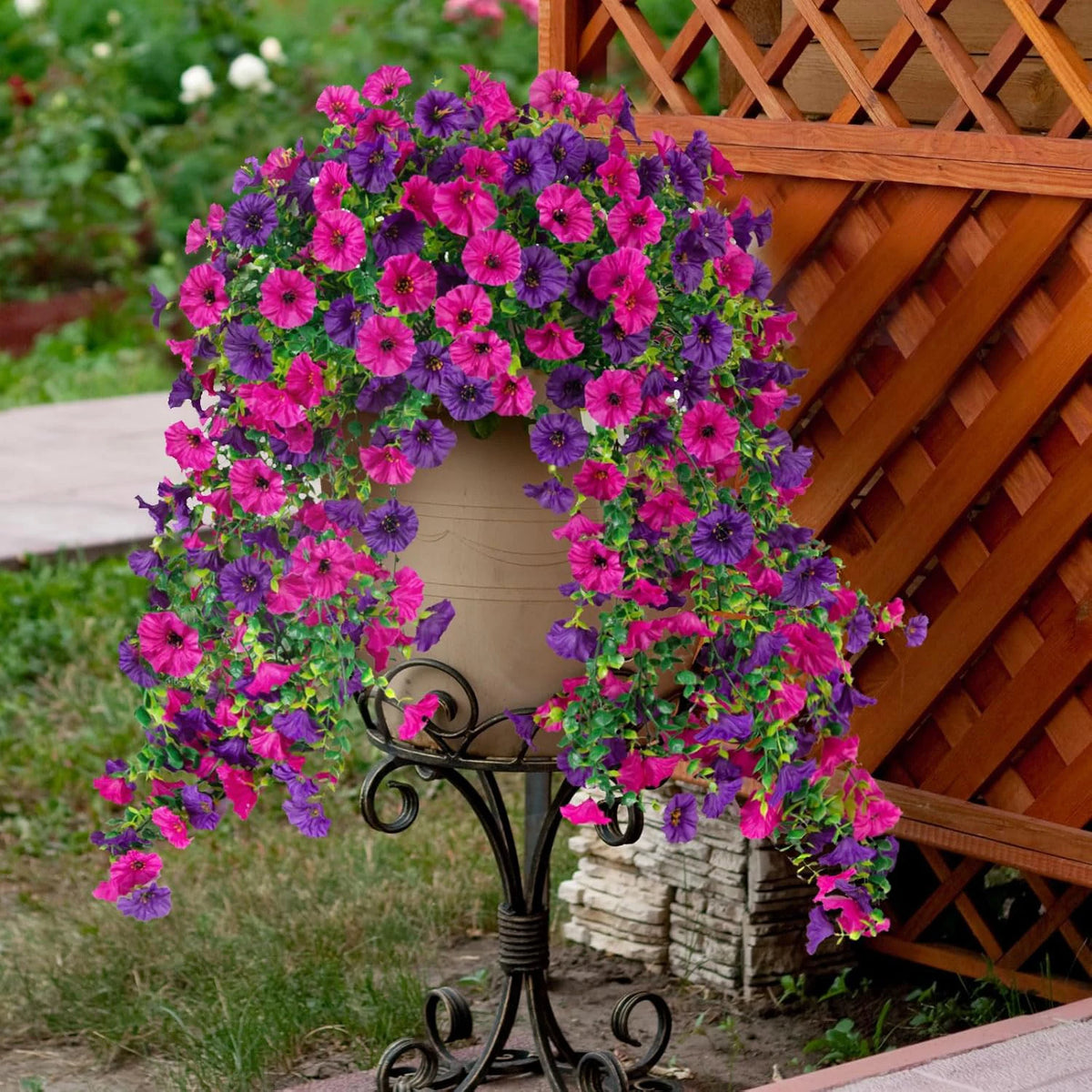 A vibrant silk morning glory vine wreath featuring pink and purple flowers draped over a terracotta urn against a wooden trel