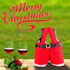 A pair of red festive Santa Claus gift bags with black straps and white soles are displayed in a green outdoor setting.