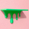A bright green liquid drip effect on a pink wall, showcasing a 3D printed floating shelf design.
