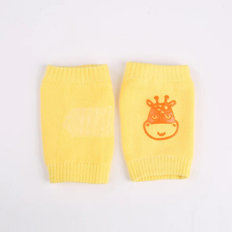 A pair of yellow knitted knee pads for crawling infants featuring an orange giraffe design.