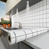 A modern kitchen featuring a white subway tile backsplash and a roll of waterproof oil-proof kitchen wall sticker on the coun