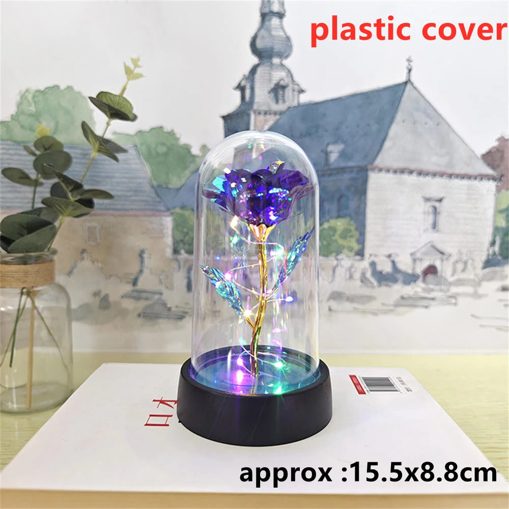 An LED galaxy rose artificial flower displayed inside a glass dome on a black base.