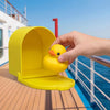 A hand is holding a yellow magnetic duck mailbox cover with a hidden duckling against a blue sea background.