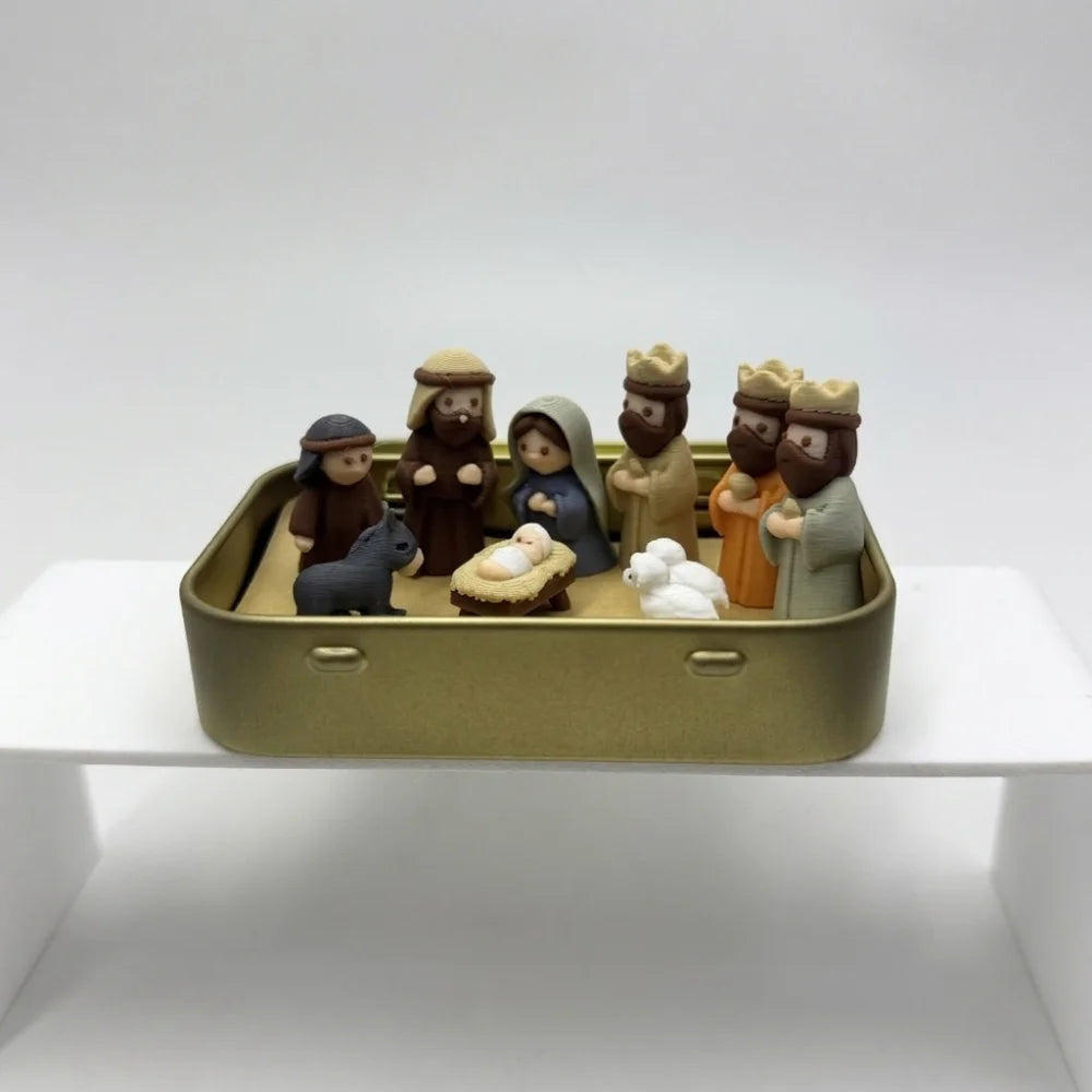 A hand-painted mini nativity set featuring figures of Mary Joseph and baby Jesus in a gold tin storage box.
