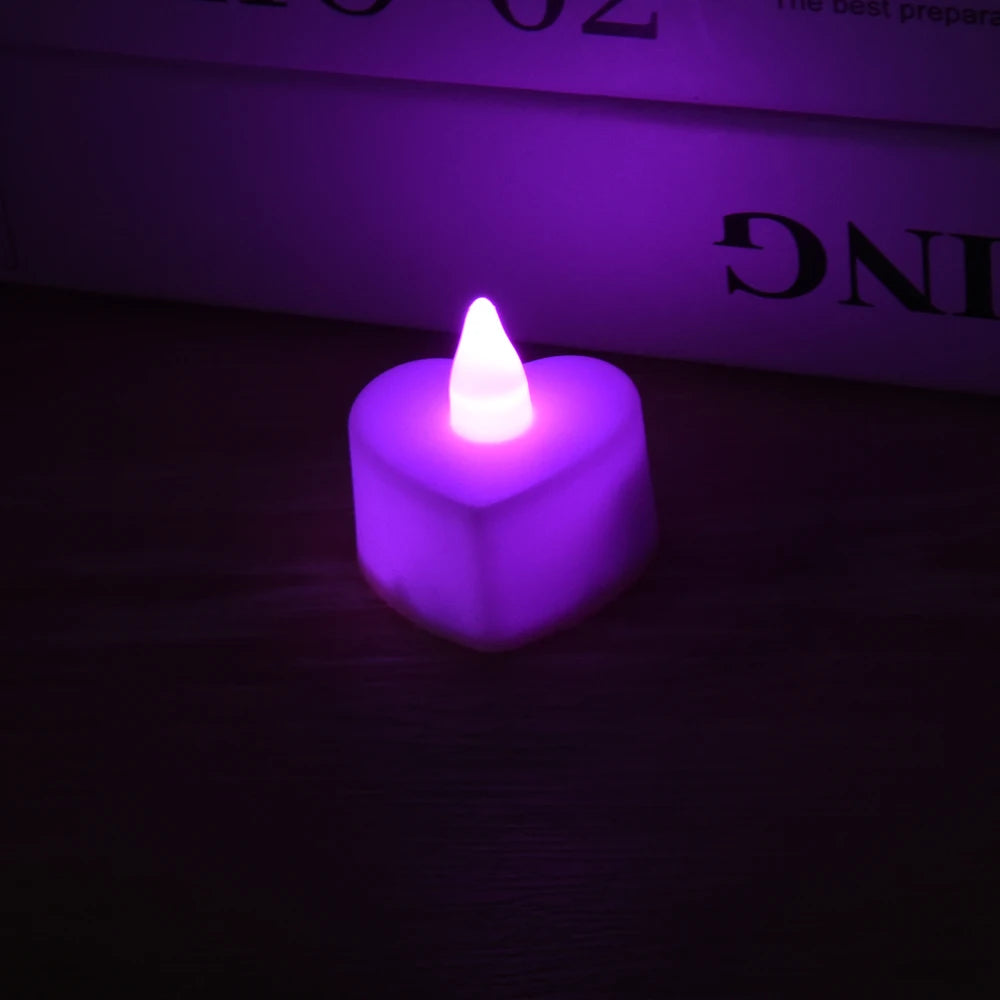 A glowing purple heart-shaped flameless LED tealight candle resting on a dark surface.