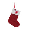 A red knitted sock with a white fabric tag featuring a red letter N and a loop for hanging.