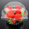 A clear plastic container filled with fresh strawberries and green leaves, topped with a transparent lid.