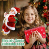 A smiling young girl holds a red electric Santa climbing rope decoration in front of a Christmas tree.