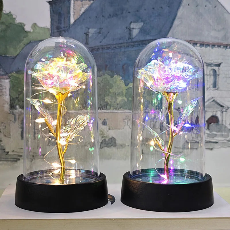 A glass dome displaying an eternal rose with glowing filaments and LED light against a blurred background.