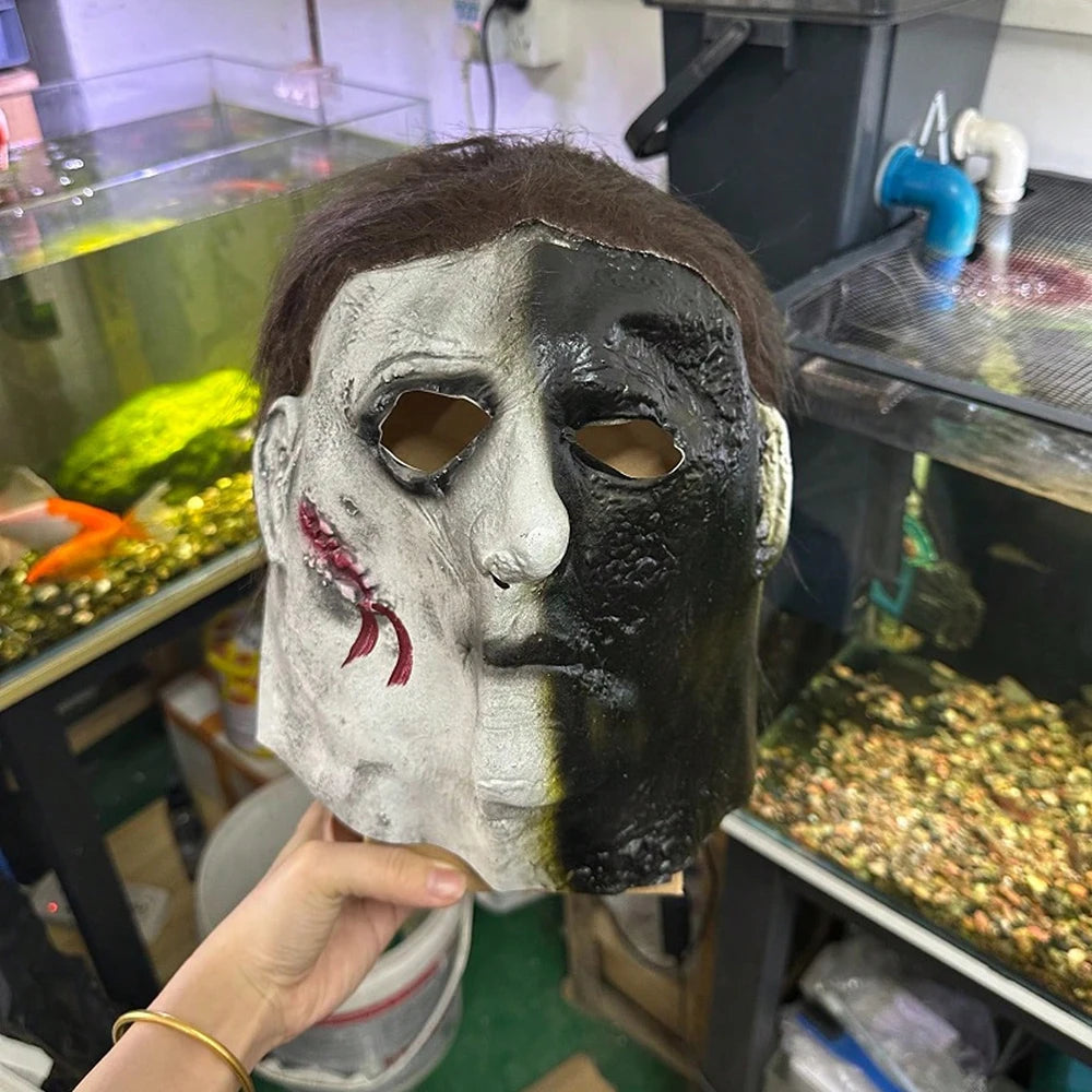 A realistic horror mask resembling Michael Myers with gray and black facial paint being held up.