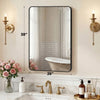 A modern wall mirror with a black metal frame reflects a white bathtub and a tiled wall in a bathroom setting.
