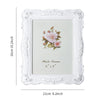 White ornate photo frame with a floral design and a rose motif, measuring 6" x 8".