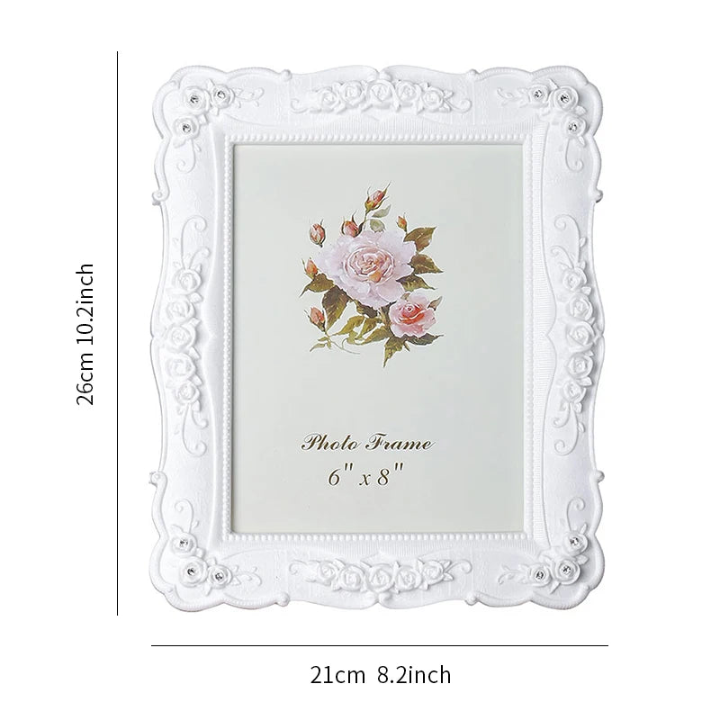 White ornate photo frame with a floral design and a rose motif, measuring 6" x 8".
