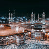 Night view of the Masjid an Nabawi in Mecca with numerous people gathered around the Kaaba.