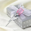 Silver crystal rose artificial flower set tied with a sheer ribbon resting on a gray gift box
