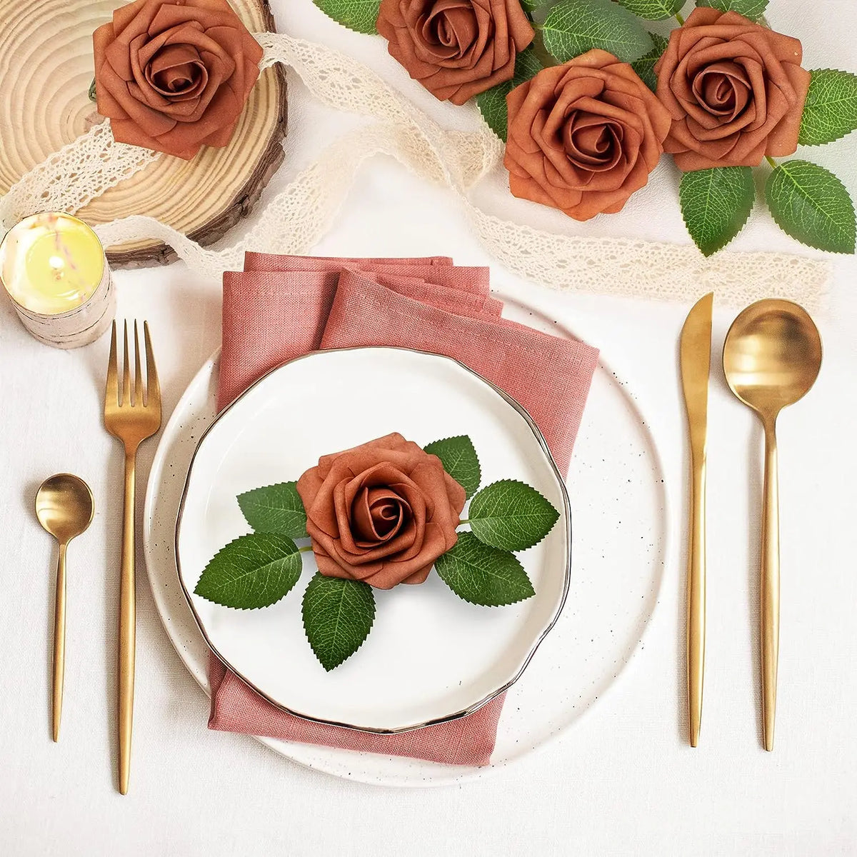 A flat lay of artificial real touch foam roses in various shades of terracotta and green on a white background.