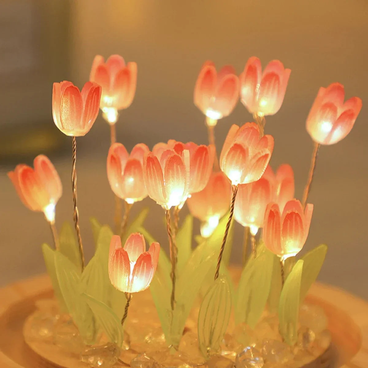 A cluster of pink and orange LED tulips glowing softly in a clear base.