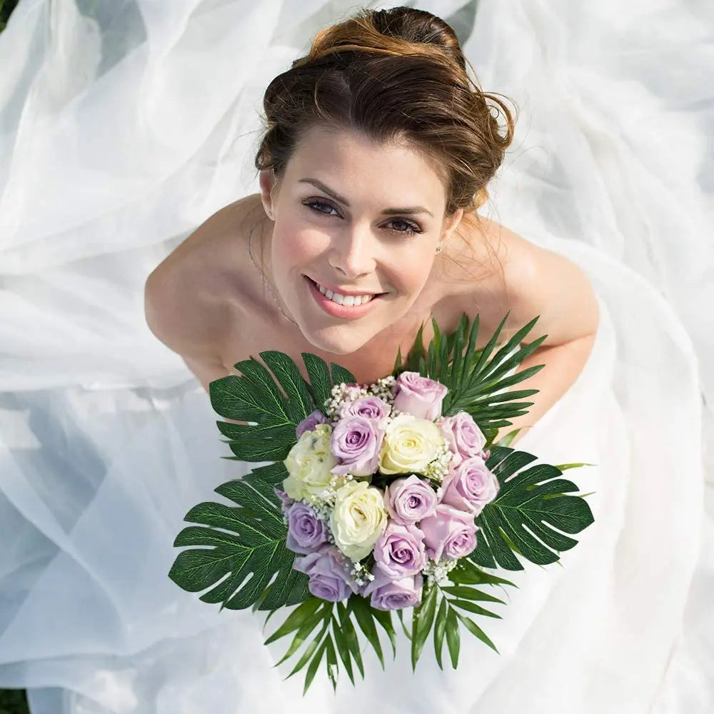A smiling woman wearing a white dress holds a bouquet of purple and white artificial tropical palm leaves for party decor.