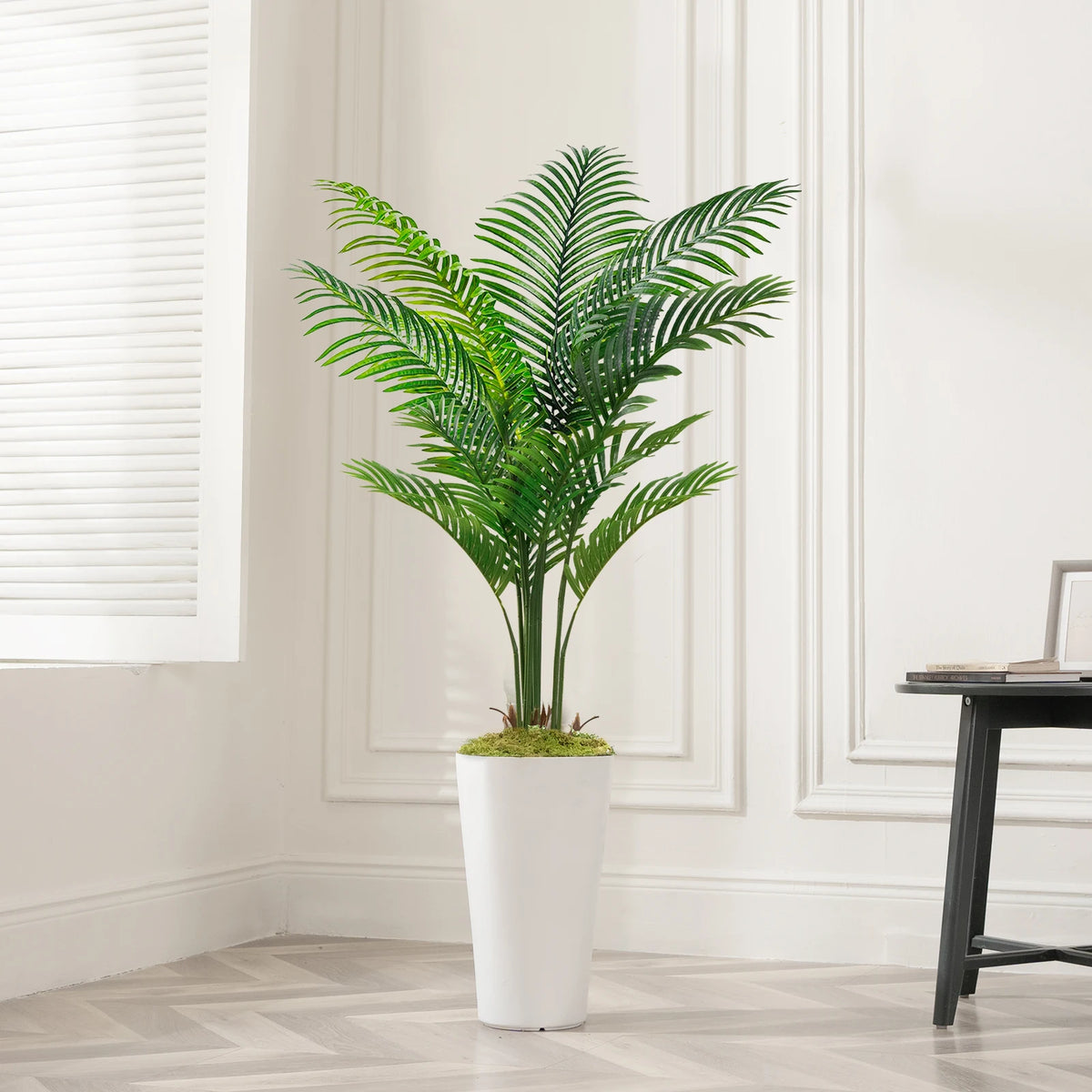 Artificial palm tree floor decor in a white pot displayed indoors next to a window.