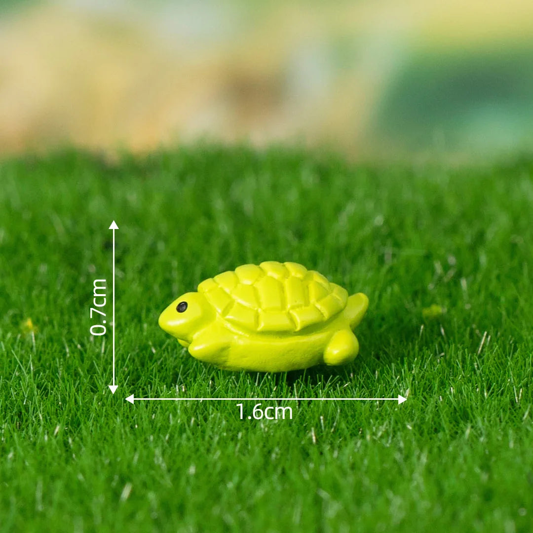 A bright yellow miniature turtle figurine resting on green grass.