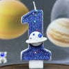 A birthday candle shaped like the number one covered in blue glitter and featuring a white planet design.