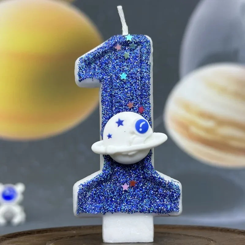 A birthday candle shaped like the number one covered in blue glitter and featuring a white planet design.