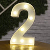 A glowing warm white LED alphabet letter light shaped like the number two resting on a wooden surface.