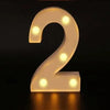 A glowing white LED alphabet night light shaped like the number 2, illuminating a dark surface.