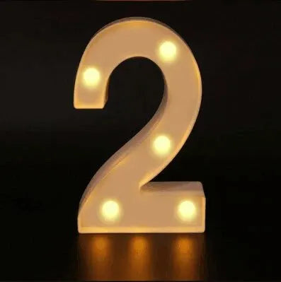 A glowing white LED alphabet night light shaped like the number 2, illuminating a dark surface.