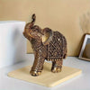 A vintage resin elephant ornament with intricate gold detailing displayed on a light wooden base.
