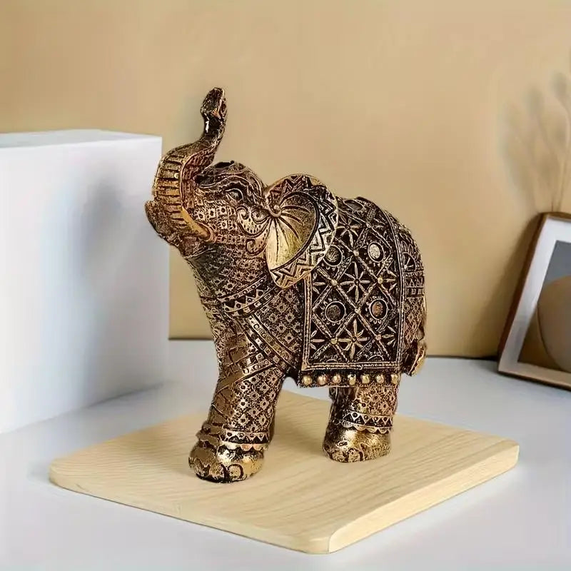 A vintage resin elephant ornament with intricate gold detailing displayed on a light wooden base.