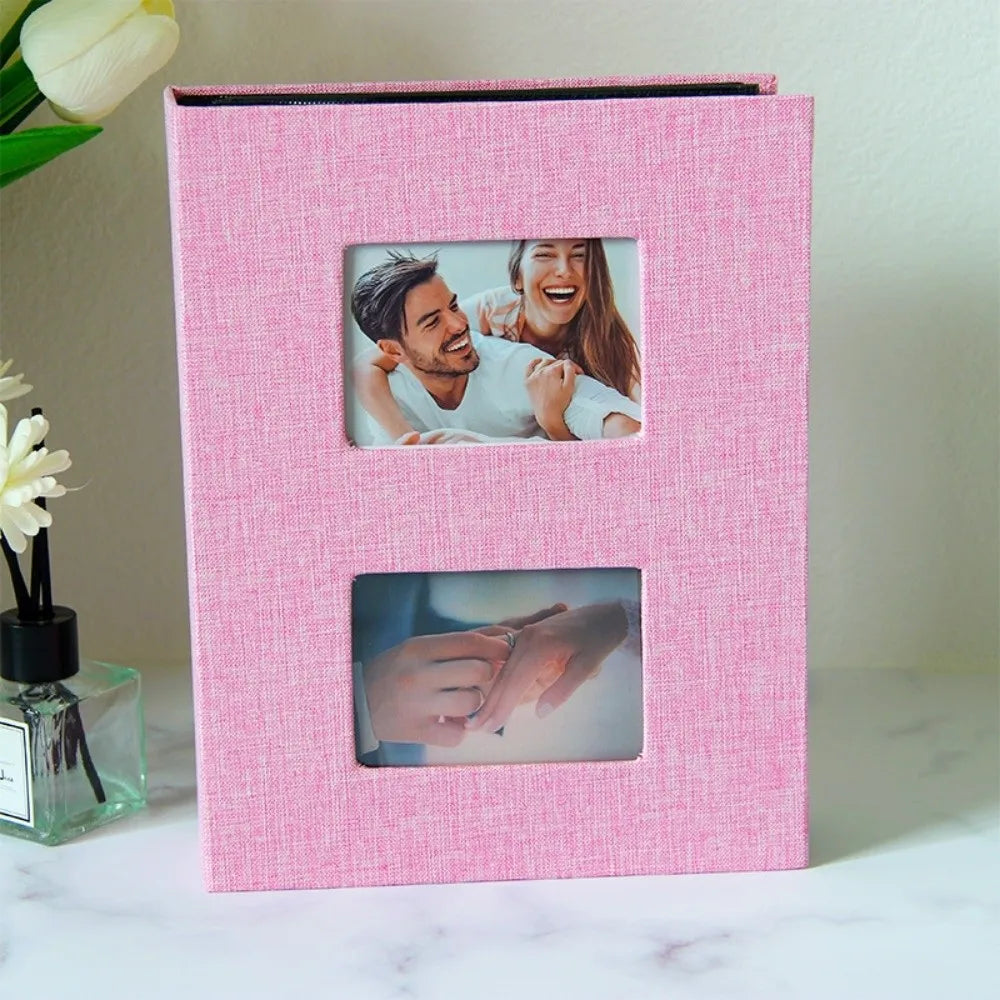 A pink linen-cover photo album with two clear pockets displaying photos of a couple.