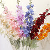Un bouquet de fleurs artificielles de delphinium dans des tons de rose, violet, bleu et rouge.