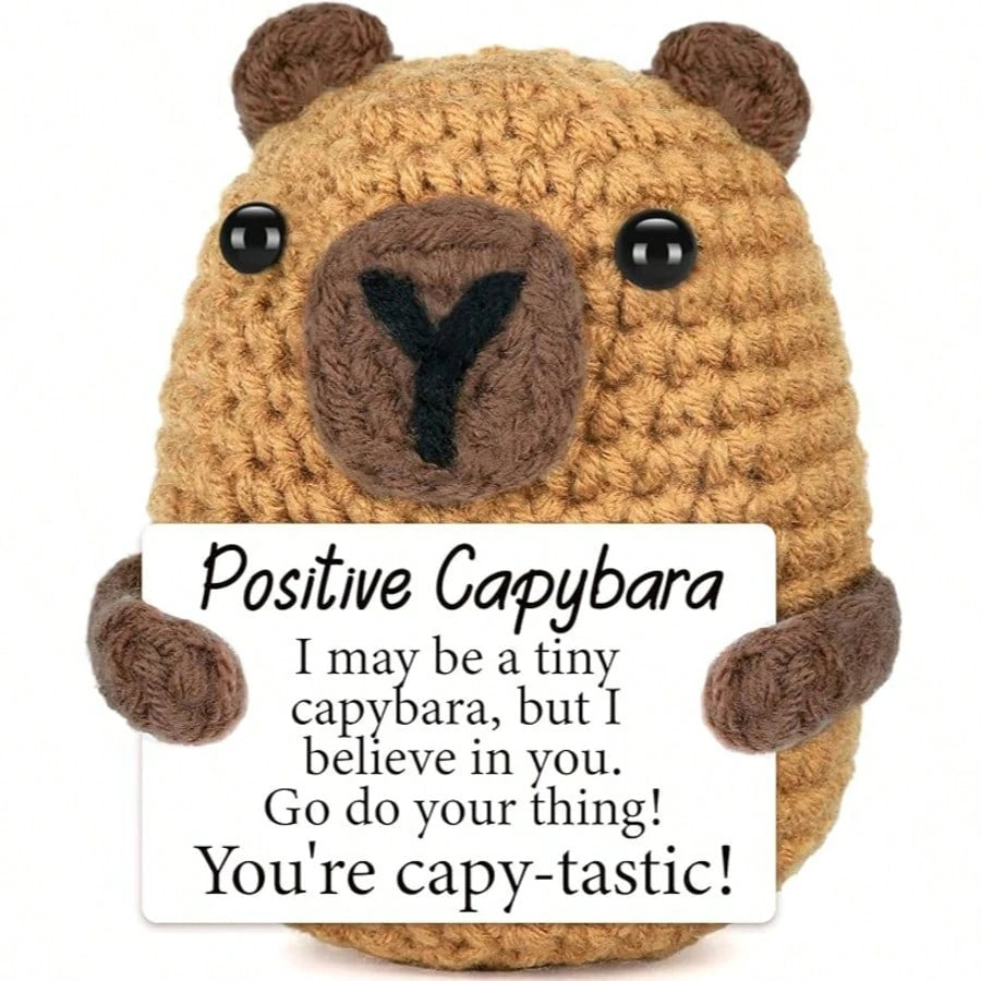 A hand-woven brown capybara plush pendant with an encouraging card that reads I believe in you and you're capy-tastic