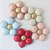 A set of five matte foil flower balloons in shades of red and pink with a daisy design.