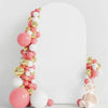 Un arco vertical hecho de globos rosas y dorados con detalles blancos contra un fondo blanco.