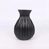 A black ceramic flower vase with a ribbed, geometric texture.