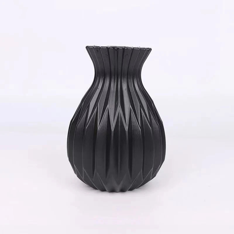 A black ceramic flower vase with a ribbed, geometric texture.