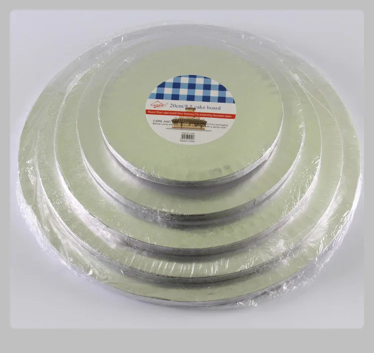 A set of round green cake boards wrapped in plastic, with one board featuring a blue and white checkered pattern.