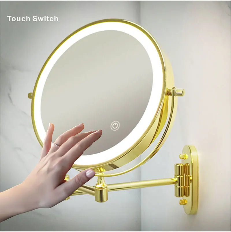 A hand is holding a round, illuminated makeup mirror with a gold frame and a light ring.